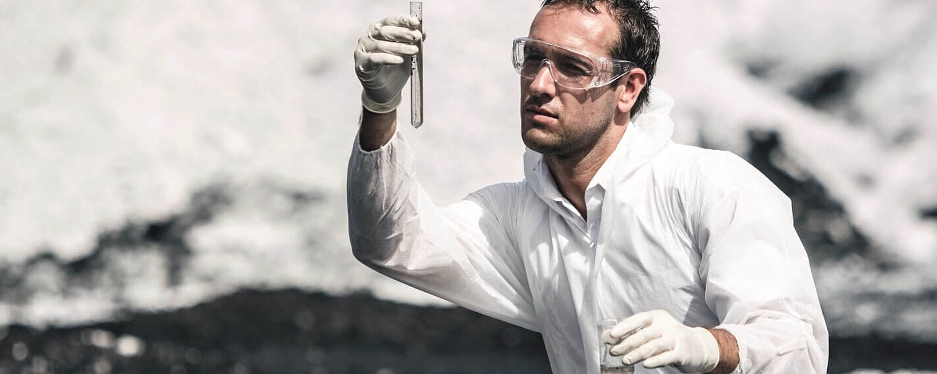 Scientist in protective gear collecting soil sample outdoors
