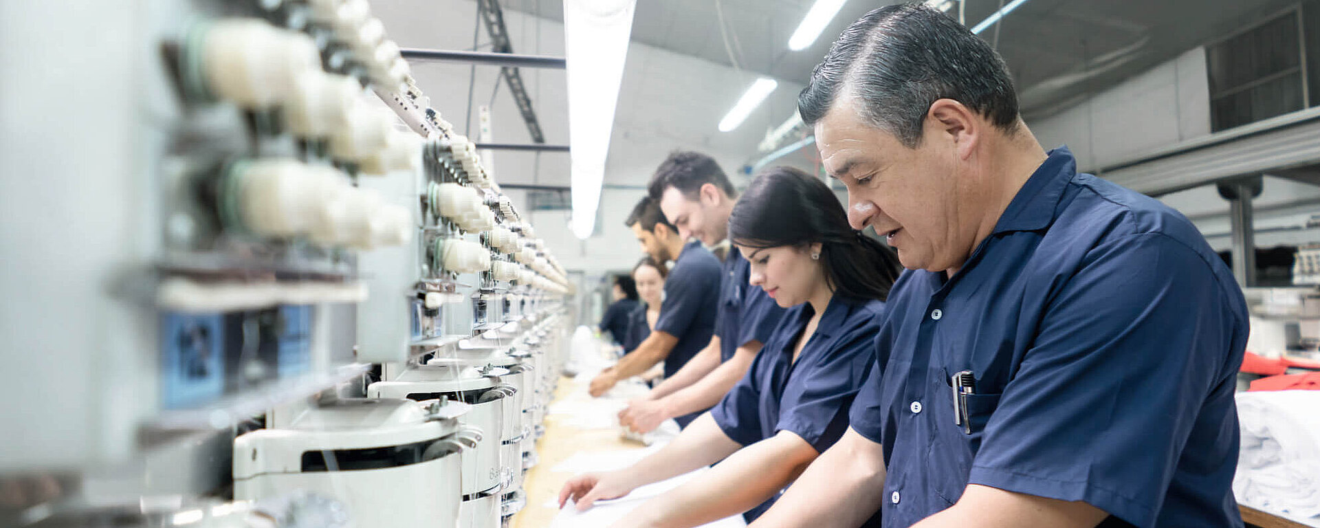 Workers in blue uniforms operating sewing machines in a textile factory